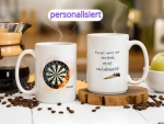Zwei weiße Keramiktassen mit personalisiertem Dart-Design. Eine Tasse zeigt eine Dartscheibe mit Flammen-Effekt und einem individuellen Namen, während die andere den motivierenden Spruch „Es ist nicht nur ein Spiel, es ist ein Lebensstil!“ mit zwei Dartpf